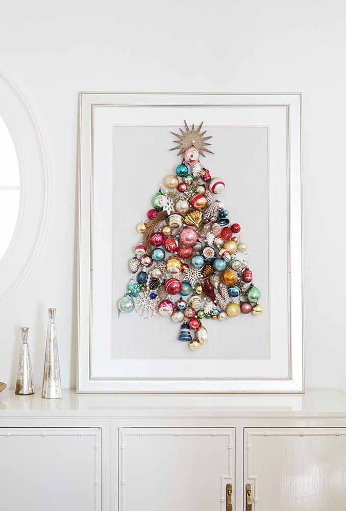 Junte vários itens decorativos de natal e monte uma árvore para colocar em um quadro