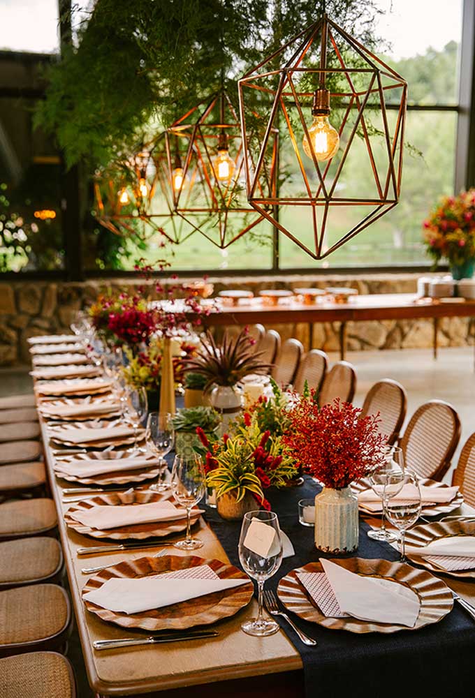 Capriche na decoração das mesas dos convidados. Use vários arranjos de flores no espaço central e invista em luminárias pendentes.