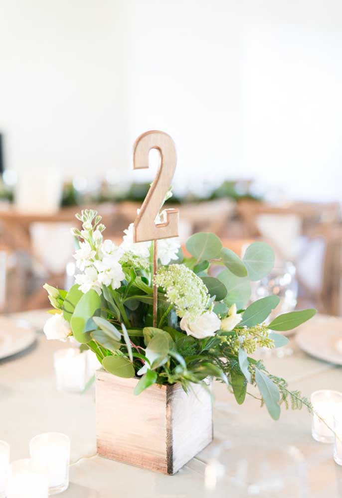 Uma boa ideia é identificar todas as mesas dos convidados. Para isso, use um vaso feito de madeira com flores e coloque um número de identificação também feito de madeira.